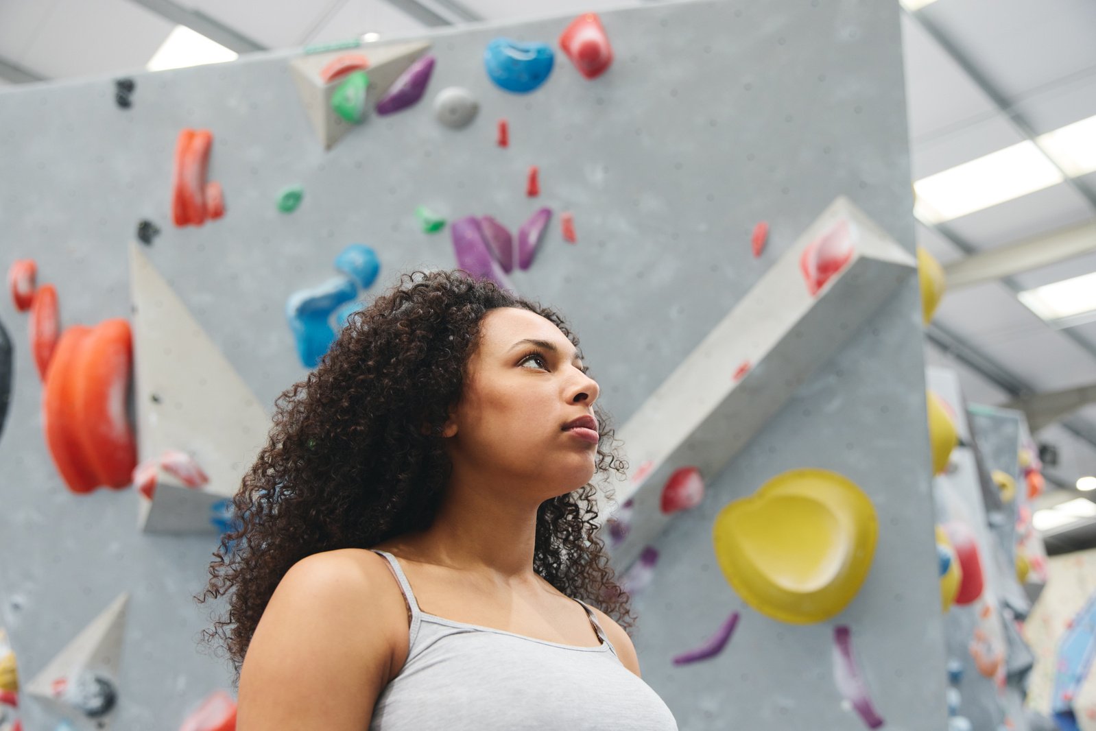 Portrait Of Confident Woman Standing At The Base Of Climbing Wall At Indoor Activity Centre