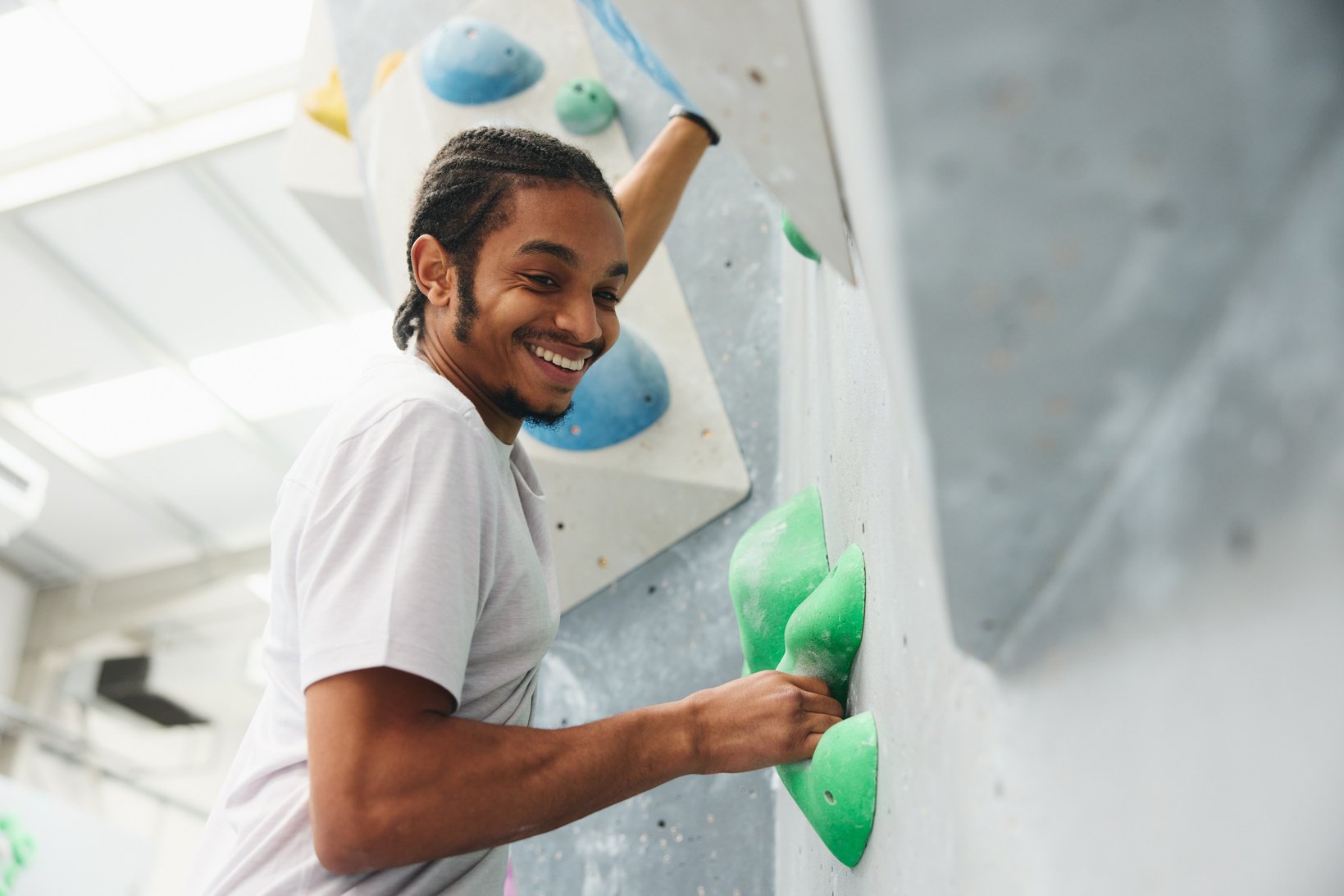 Close Up Of Smiling Man Enjoying Climbing Wall In Indoor Activity Centre