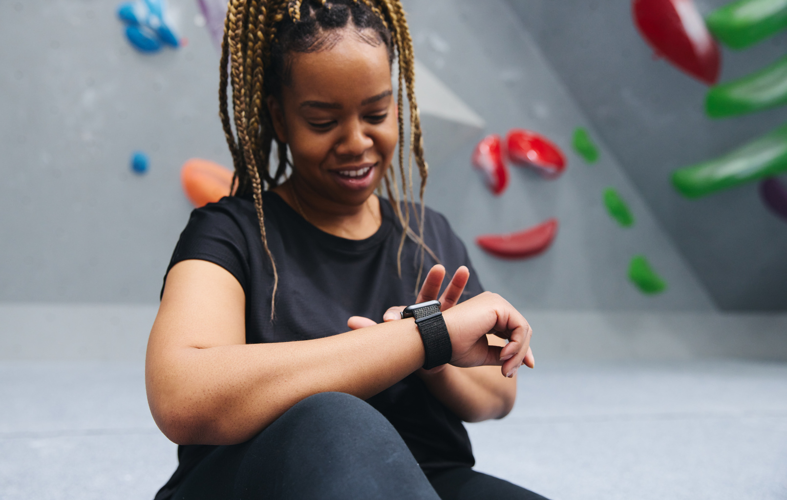 Woman By Climbing Wall At Indoor Activity Centre Checking Fitness App On Smart Watch